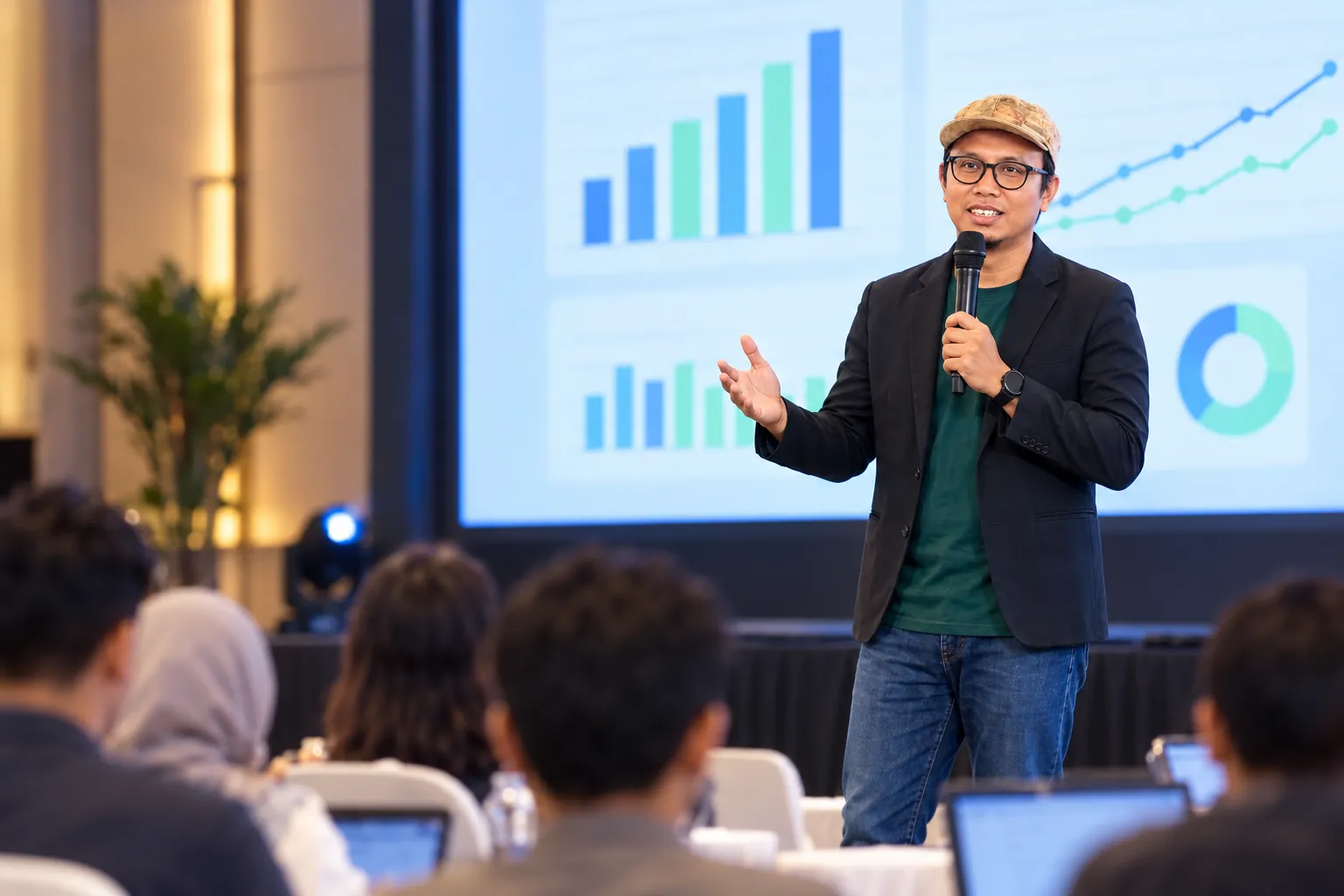 Ari Eko Prasethio memegang mikrofon dan berbicara di depan peserta seminar.